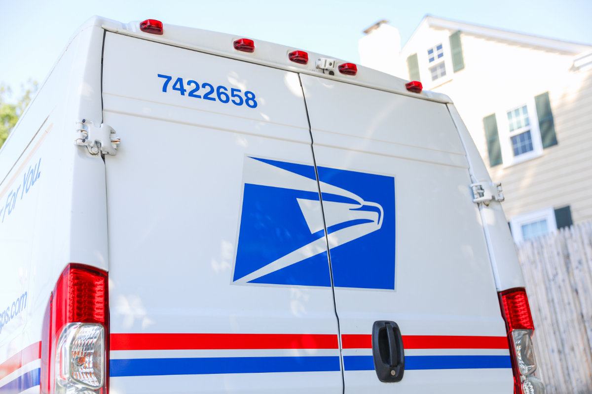 A USPS delivery vehicle parked in a residential neighborhood.